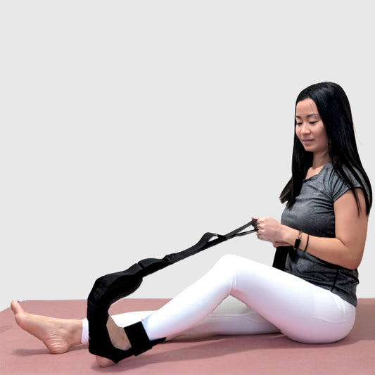Woman using a foot and calf stretcher yoga strap to stretch calves and feet; ideal as a foot rocker calf stretcher, plantar fasciitis stretch device, calf rocker, and foot stretcher for Achilles tendonitis and muscle recovery.