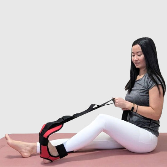 Woman using a red foot and calf stretcher with yoga straps to relieve plantar fasciitis, Achilles tendonitis, tight calves, and hamstring tension—versatile foot rocker stretcher and calf stretch device for improved flexibility and recovery.